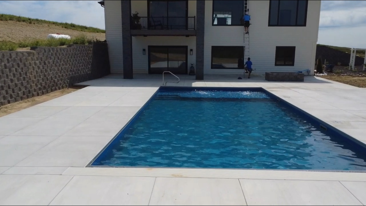 Aerial view of rectangular pool with paver patio and landscaping beds